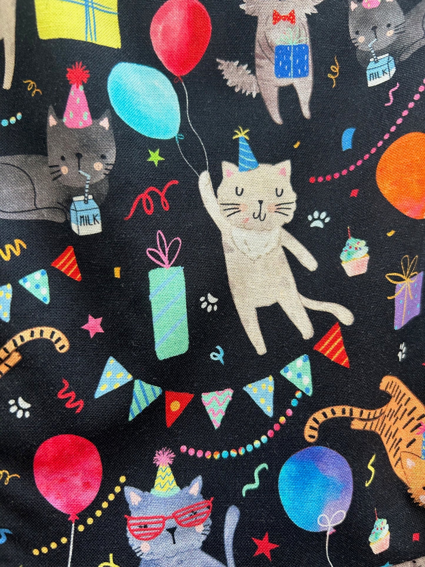 a close up of the fabric of the party cats fit and flare dress showing cats in party hats, gifts, balloons and other festive decorations