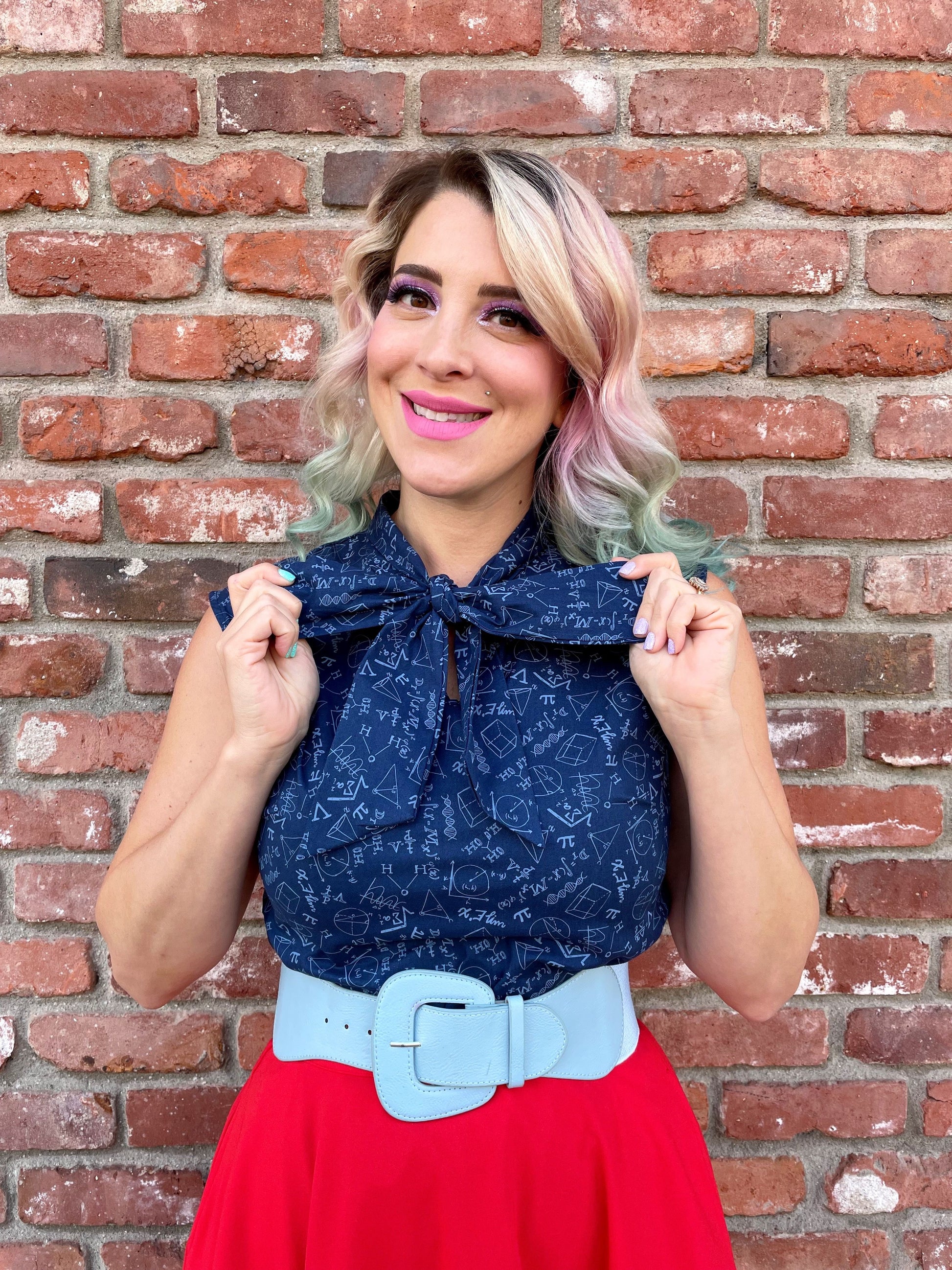 a close up of a model standing in front of a brick wall wearing our STEM bow top