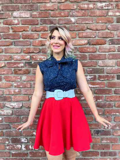 an above the knee image of a model standing in front of a brick wall wearing our STEM bow top