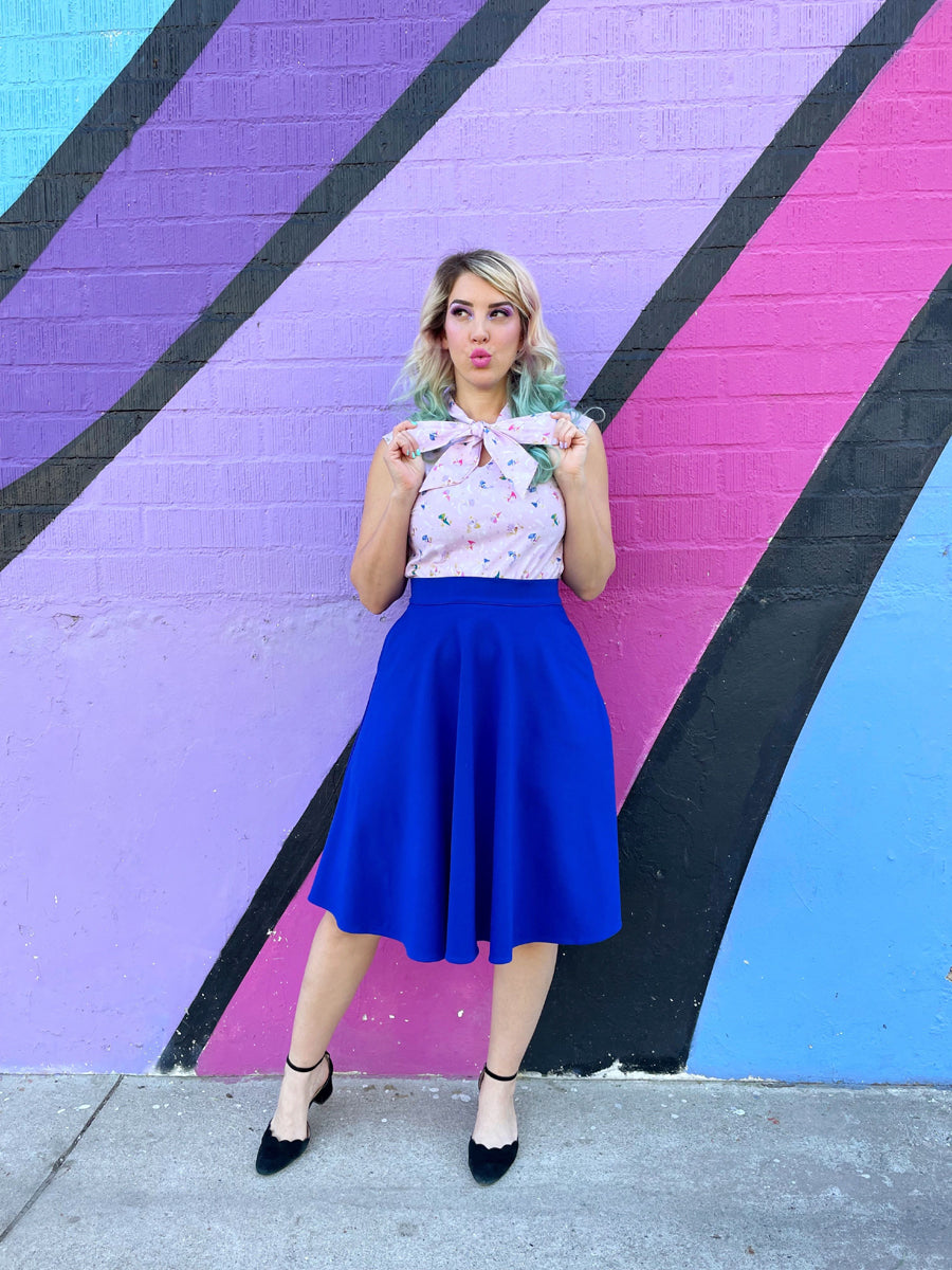 a model standing in front of a painted wall wearing a charlotte skirt in royal blue 