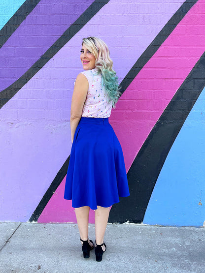 a back view of model standing in front of pained wall wearing the charlotte skirt in royal blue