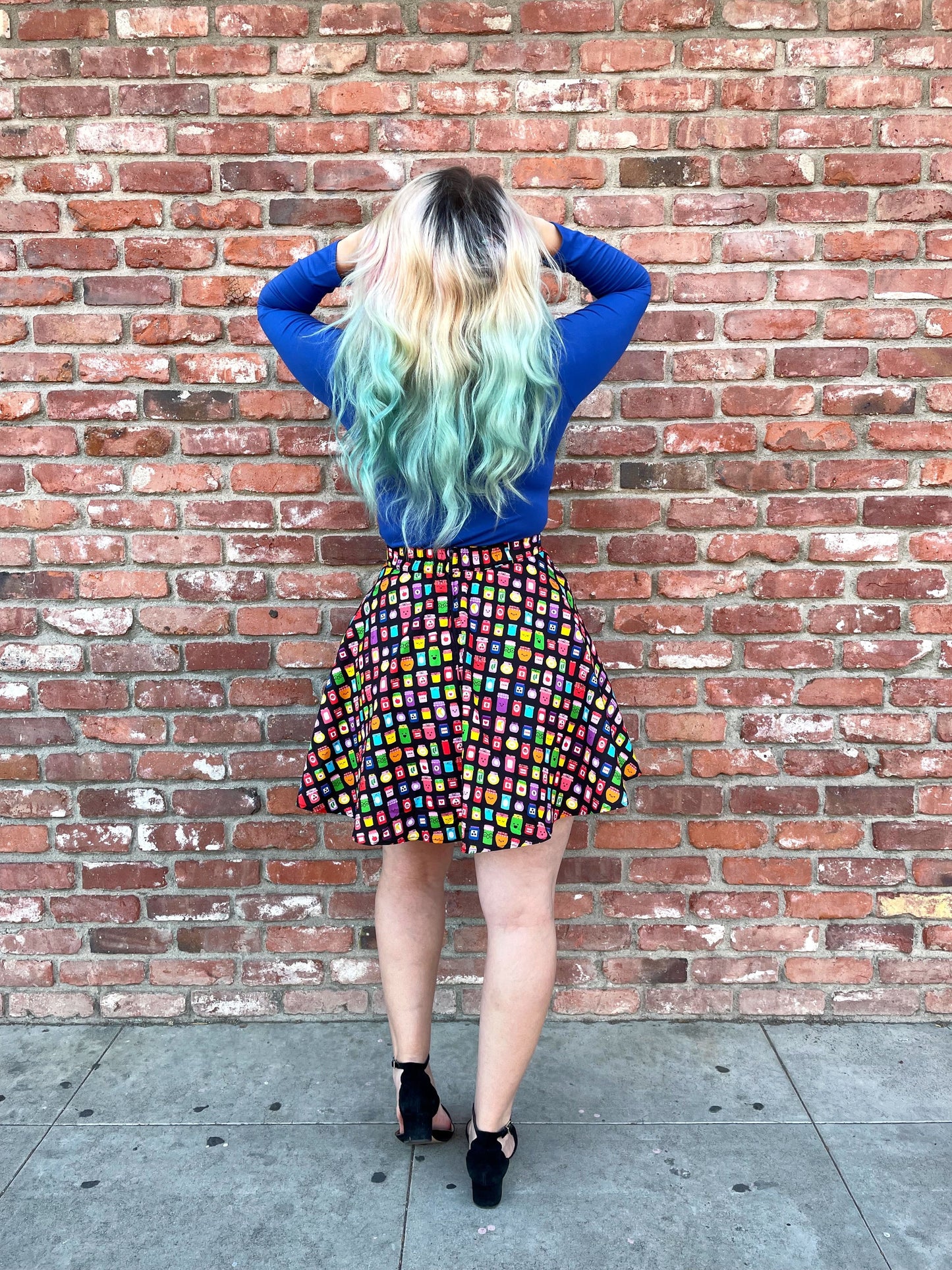 a back view of model standing in front of a brick wall wearing that's my jam skater skirt