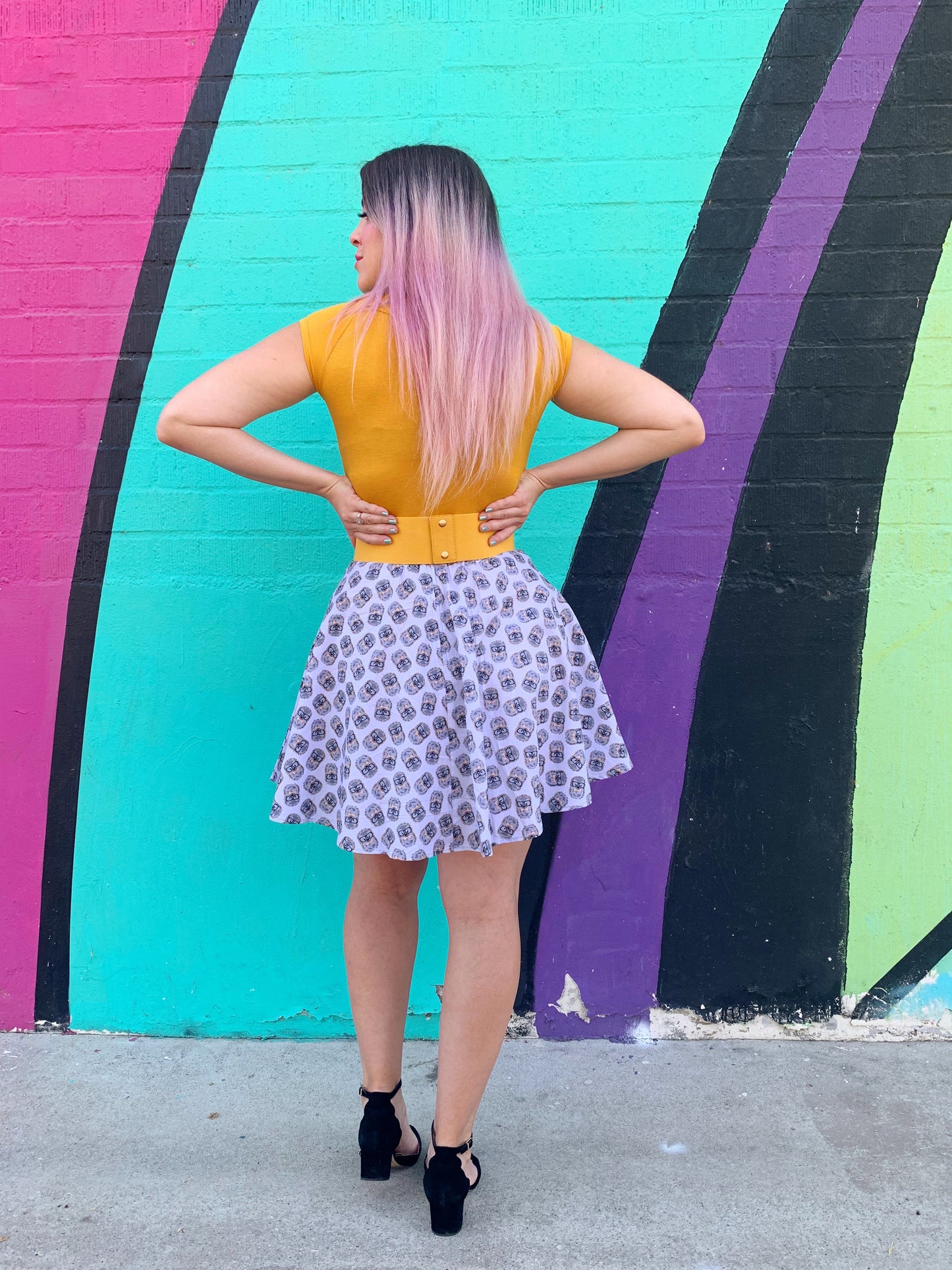 a back view of model standing in front of a colorful painted wall wearing the Hedgehog Skater Skirt 