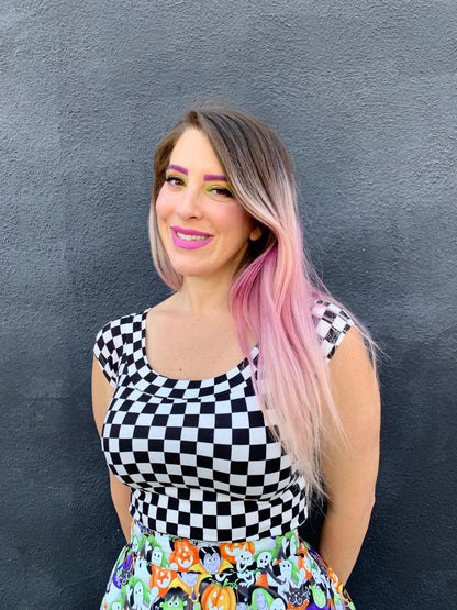 close up of model standing in front of a black wall wearing our boat neck top in checkers