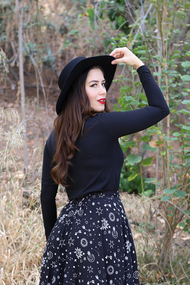 Back shot of model wearing retro outfit featuring a black stretch knit top with skirt