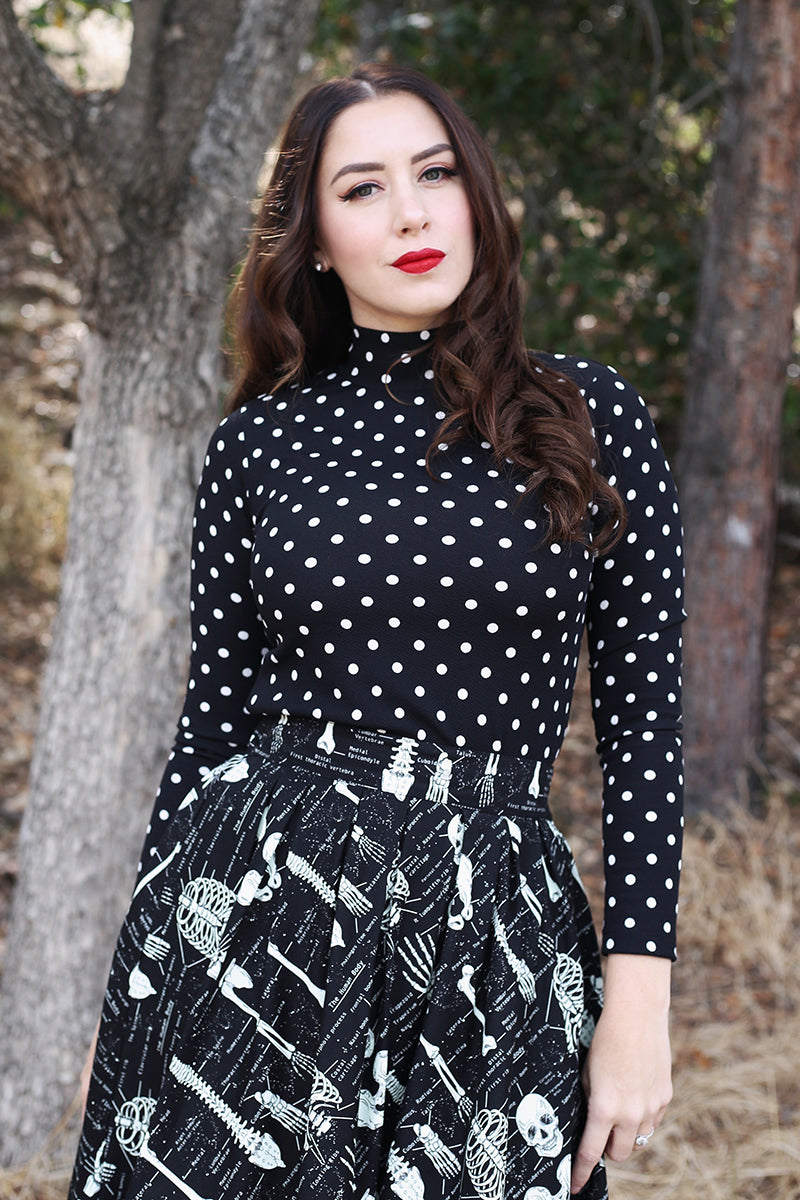 Model wearing polka dot black top while posing in the wilderness