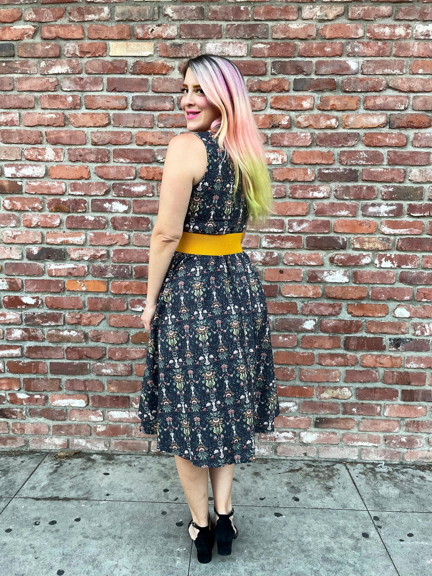 a full length image of a back of a model standing in front of a brick wall wearing the Rabbit Midi dress