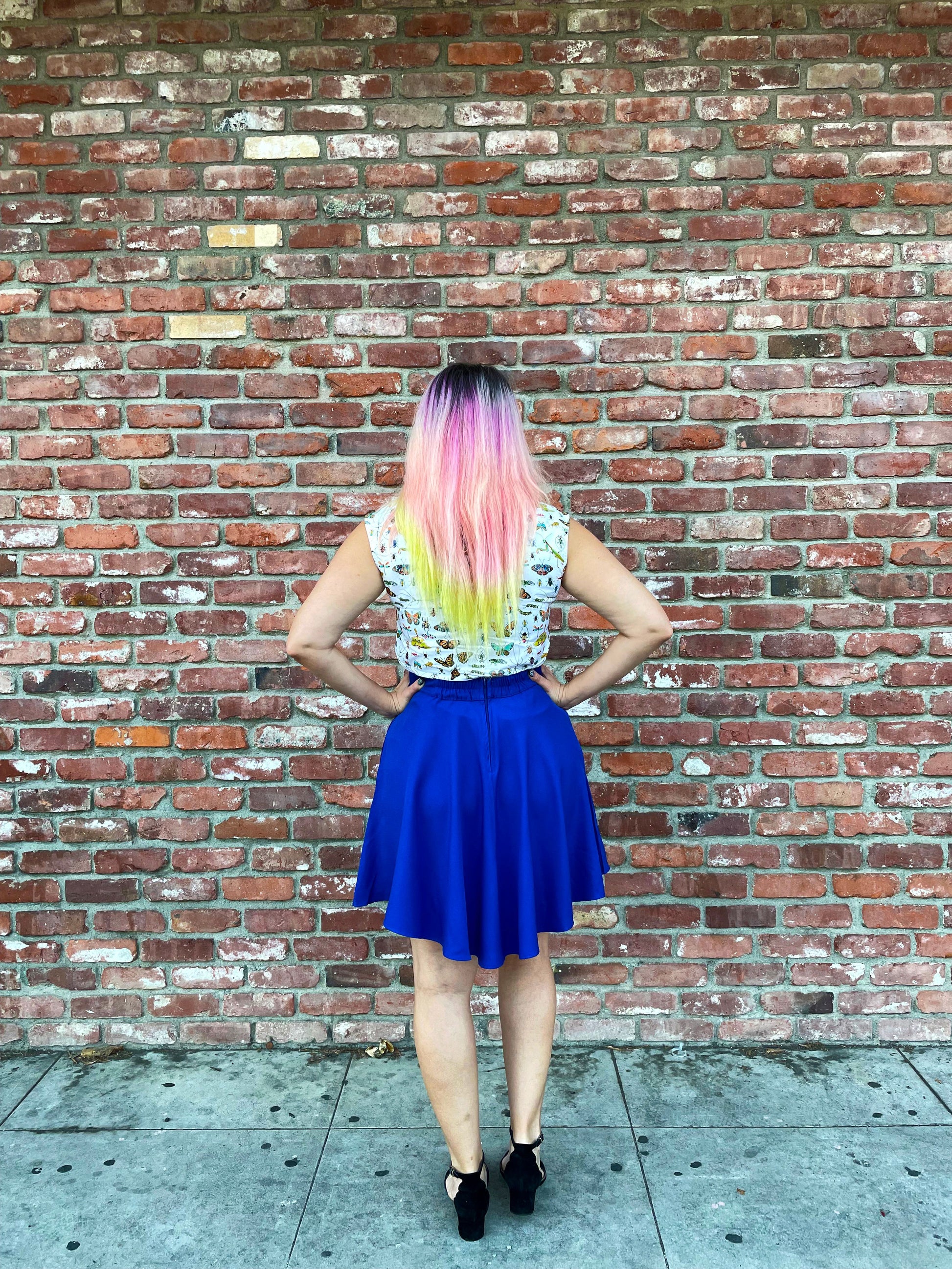 a back view of model in front of brick wall wearing the royal blue skater skirt