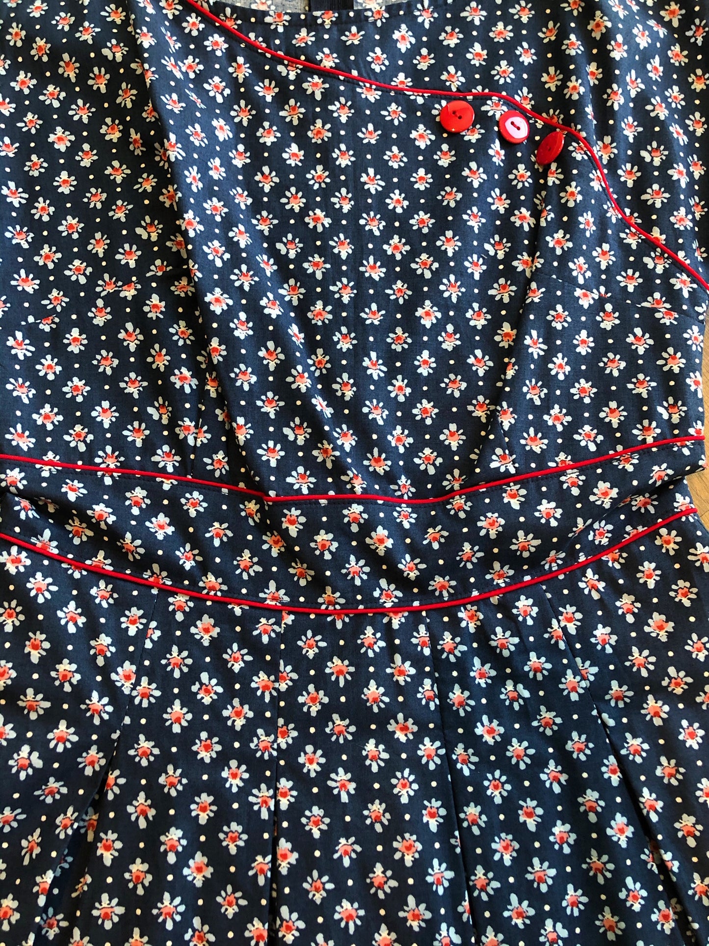 a close up showing the flower pattern on navy blue with red buttons and piping